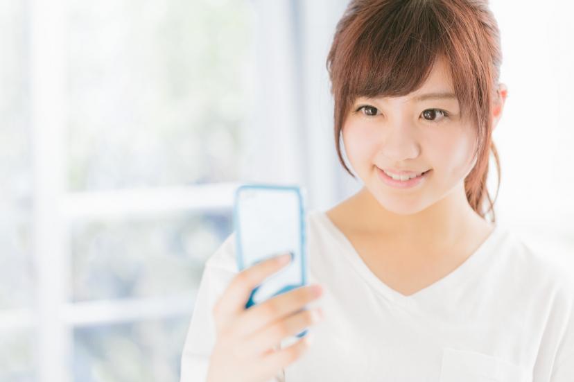 スマートフォンを片手に笑顔の女性